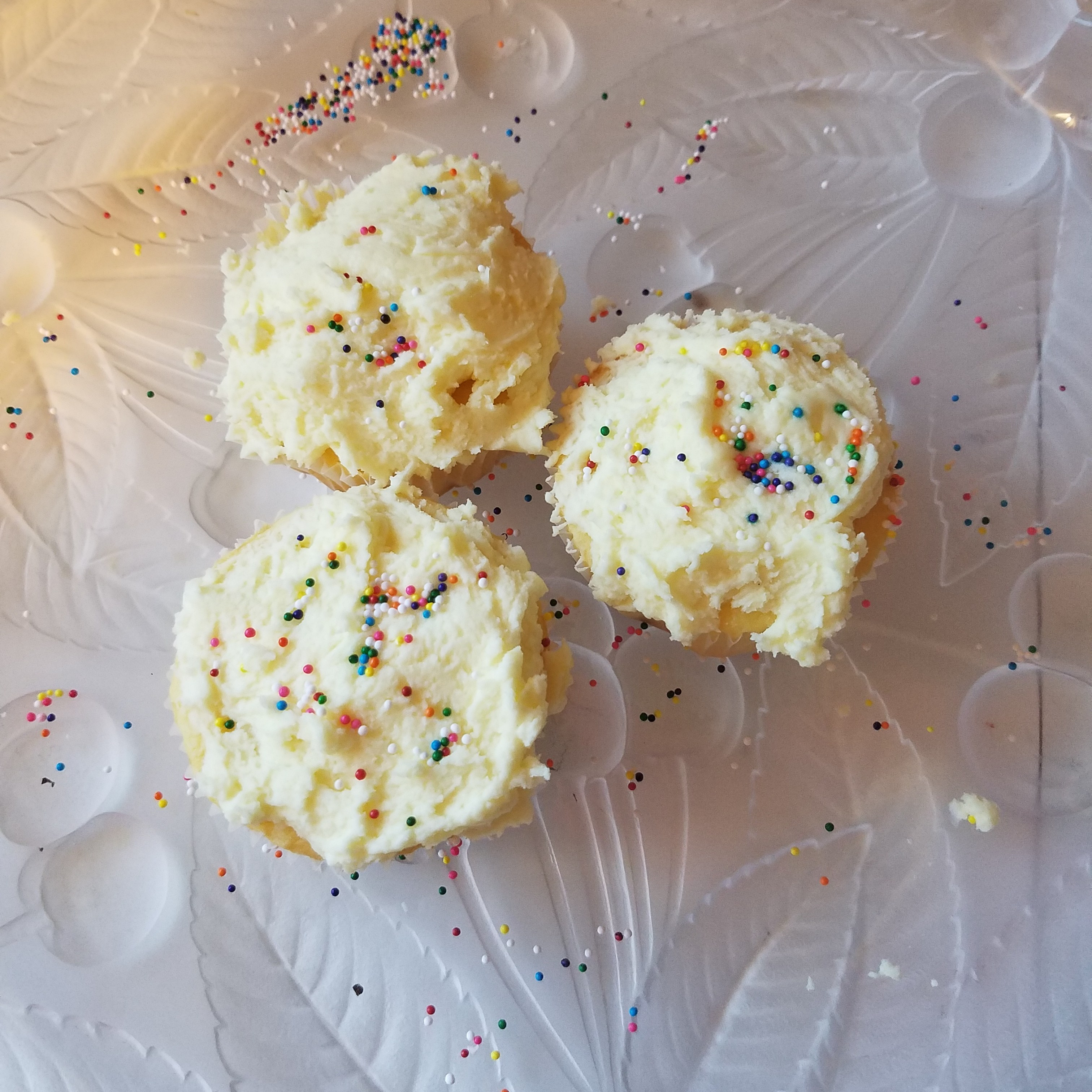three lemon cupcakes on a glass plate